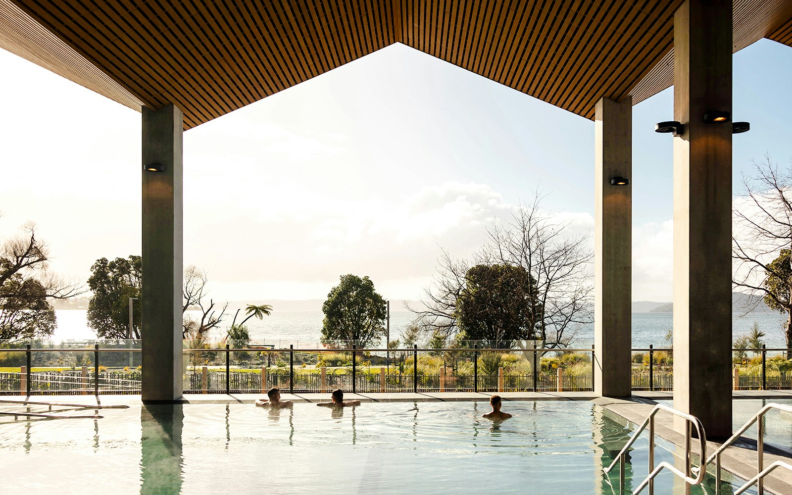 Wai Ariki Hot Springs & Spa indoor pool with lake view and visitors relaxing.