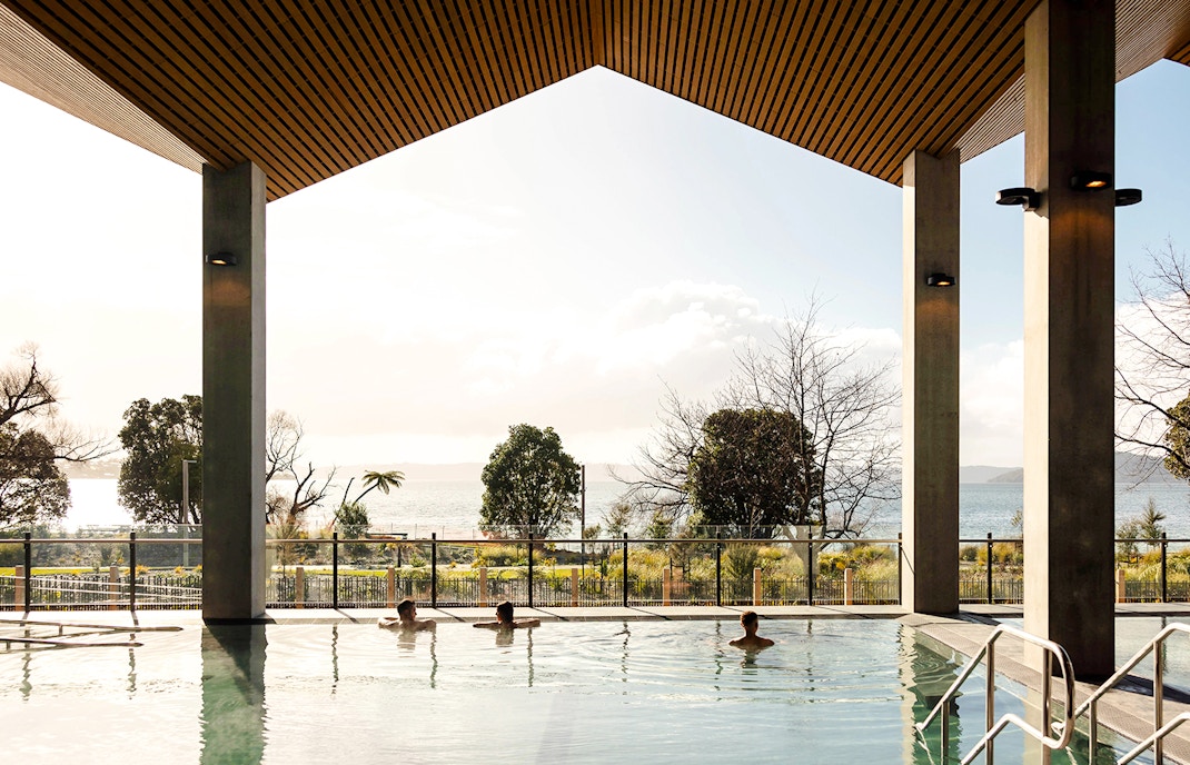 Wai Ariki Hot Springs & Spa indoor pool with lake view and visitors relaxing.