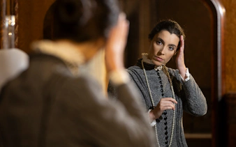 Woman in period costume adjusting hair in front of a mirror at the Palace of Pena, Portugal.