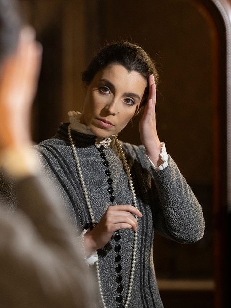Woman in period costume adjusting hair in front of a mirror at the Palace of Pena, Portugal.