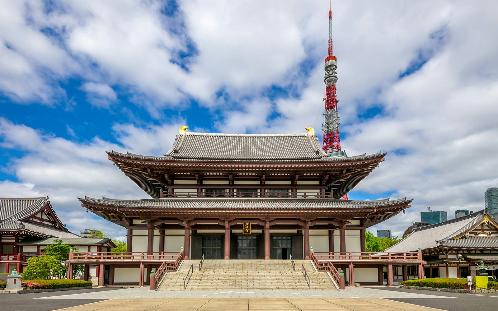 Der Zojoji-Tempel in Tokio mit traditioneller Architektur, im Hintergrund die Tokyo Tower unter einem bewölkten Himmel