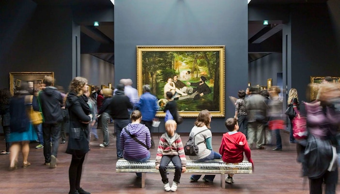 People in front of The Luncheon on the Grass painting by Édouard Manet