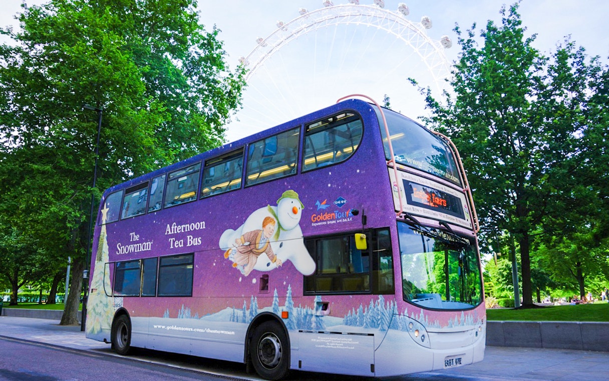 Double-decker bus with "The Snowman Afternoon Tea" design near the London Eye.