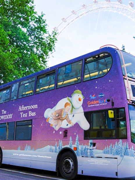 Double-decker bus with "The Snowman Afternoon Tea" design near the London Eye.