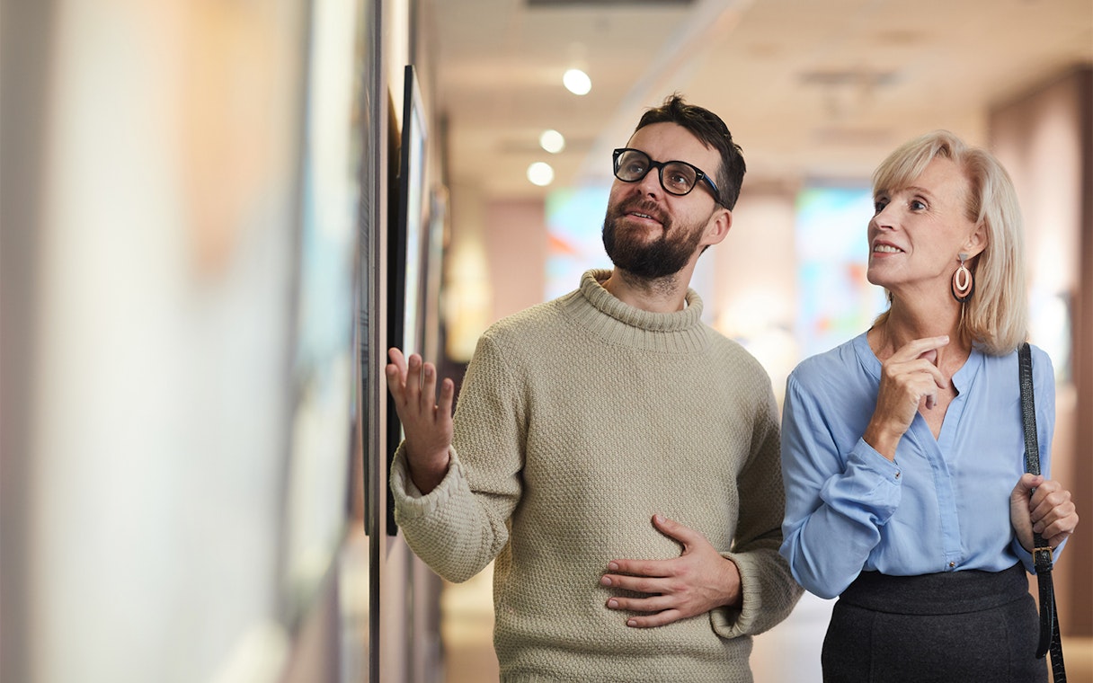 Visitors admiring artwork in a museum gallery.