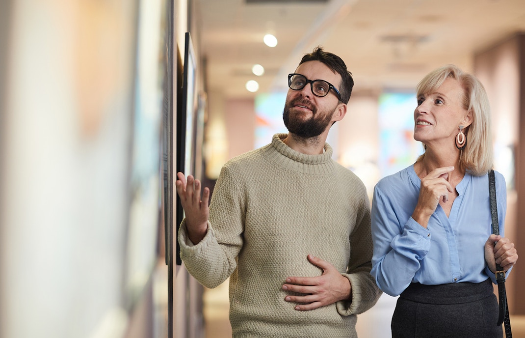 Visitors exploring art exhibits in a museum gallery.
