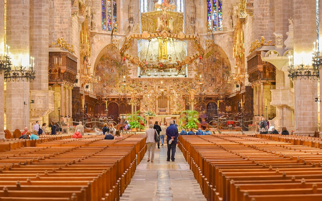 Palma Cathedral interior with ornate altar and stained glass windows.