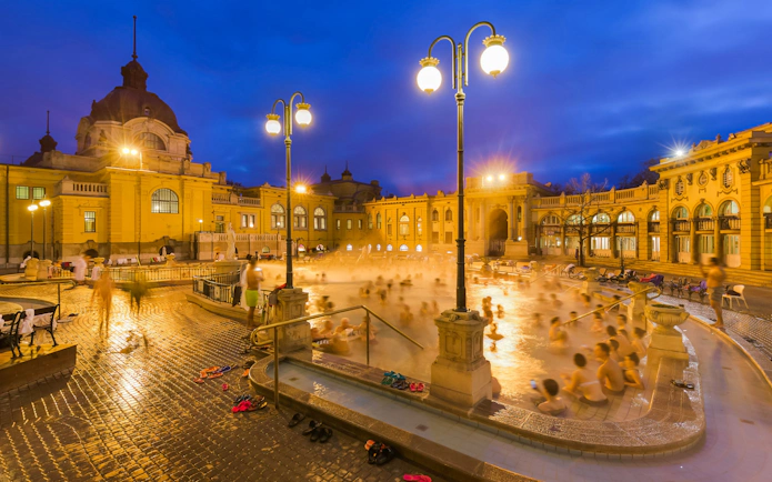 Szechenyi Thermal Bath evening view with visitors in Budapest, Hungary.