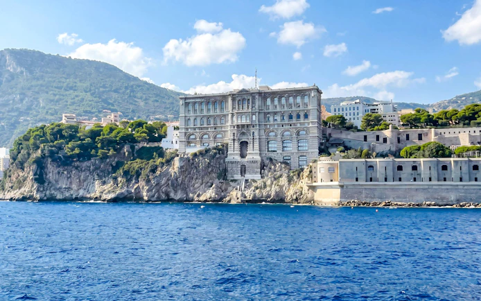 Monaco's Oceanographic Museum on a cliffside, viewed from the sea during a Villefranche boat tour.