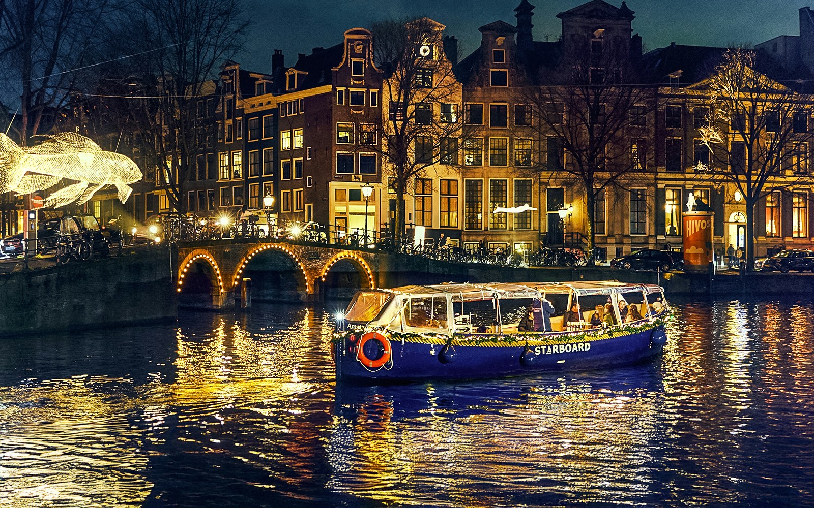 Small-group cruise on Amsterdam canal during Light Festival with illuminated art and historic buildings.
