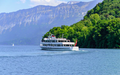 Passenger ship cruising on Lake Thun, Switzerland, with mountains in the background.