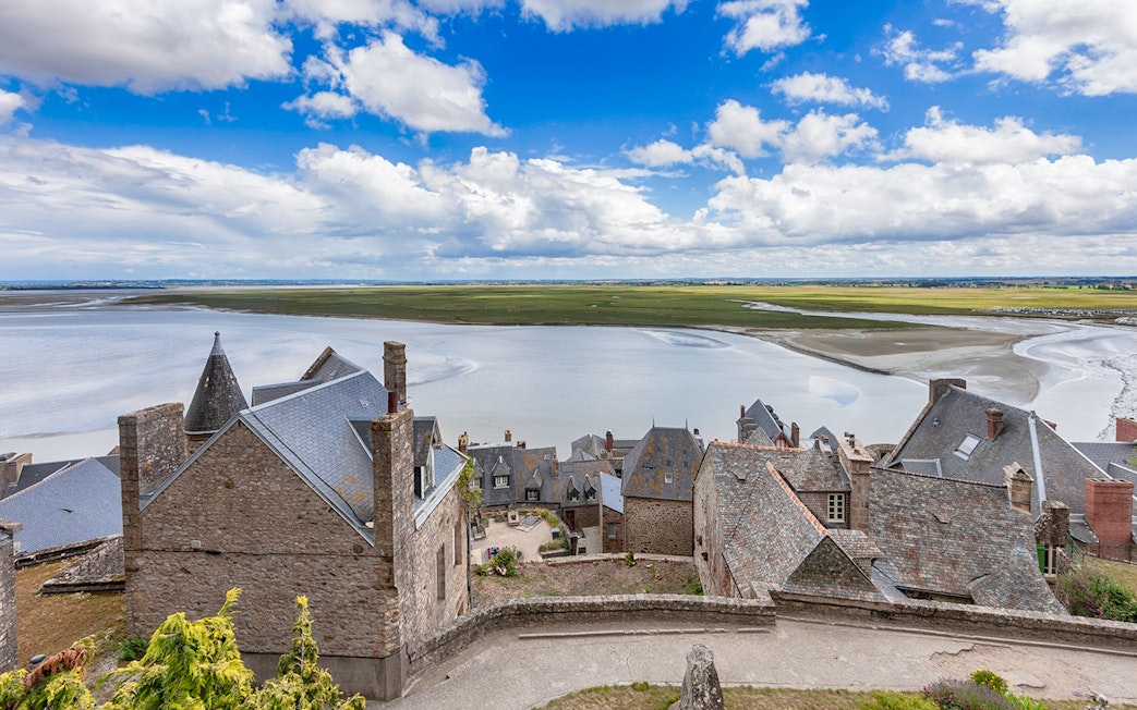 Rooftops of Mont St. Michel overlooking tidal flats and sea, seen on a full day tour from Paris.