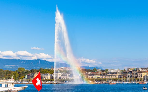 Jet d'Eau fountain in Geneva with Swiss flag boat on Lake Geneva.