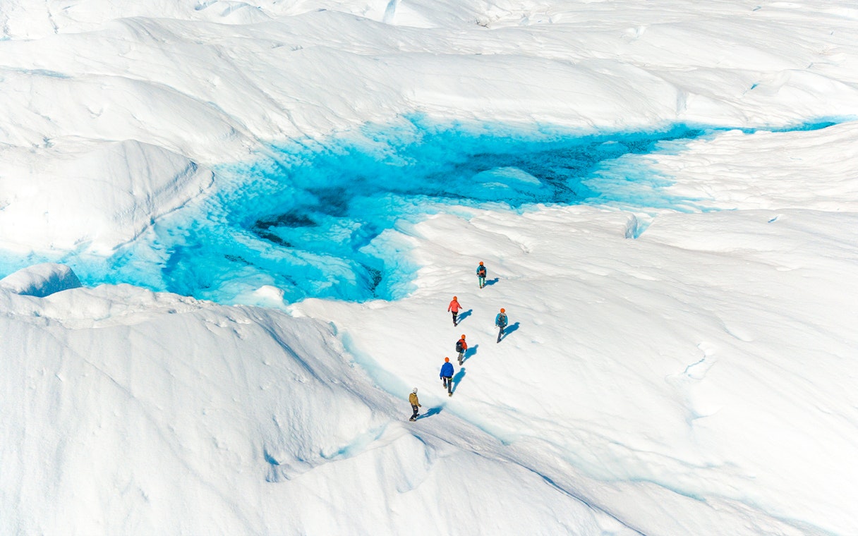 Tourists hiking on Perito Moreno Glacier near a vivid blue ice formation in Argentina.