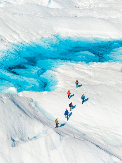 Tourists hiking on Perito Moreno Glacier near a vivid blue ice formation in Argentina.