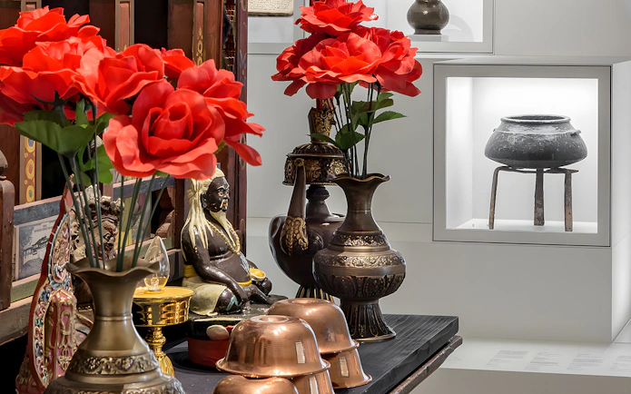 Artifacts and red flowers displayed at Weltmuseum, Vienna.