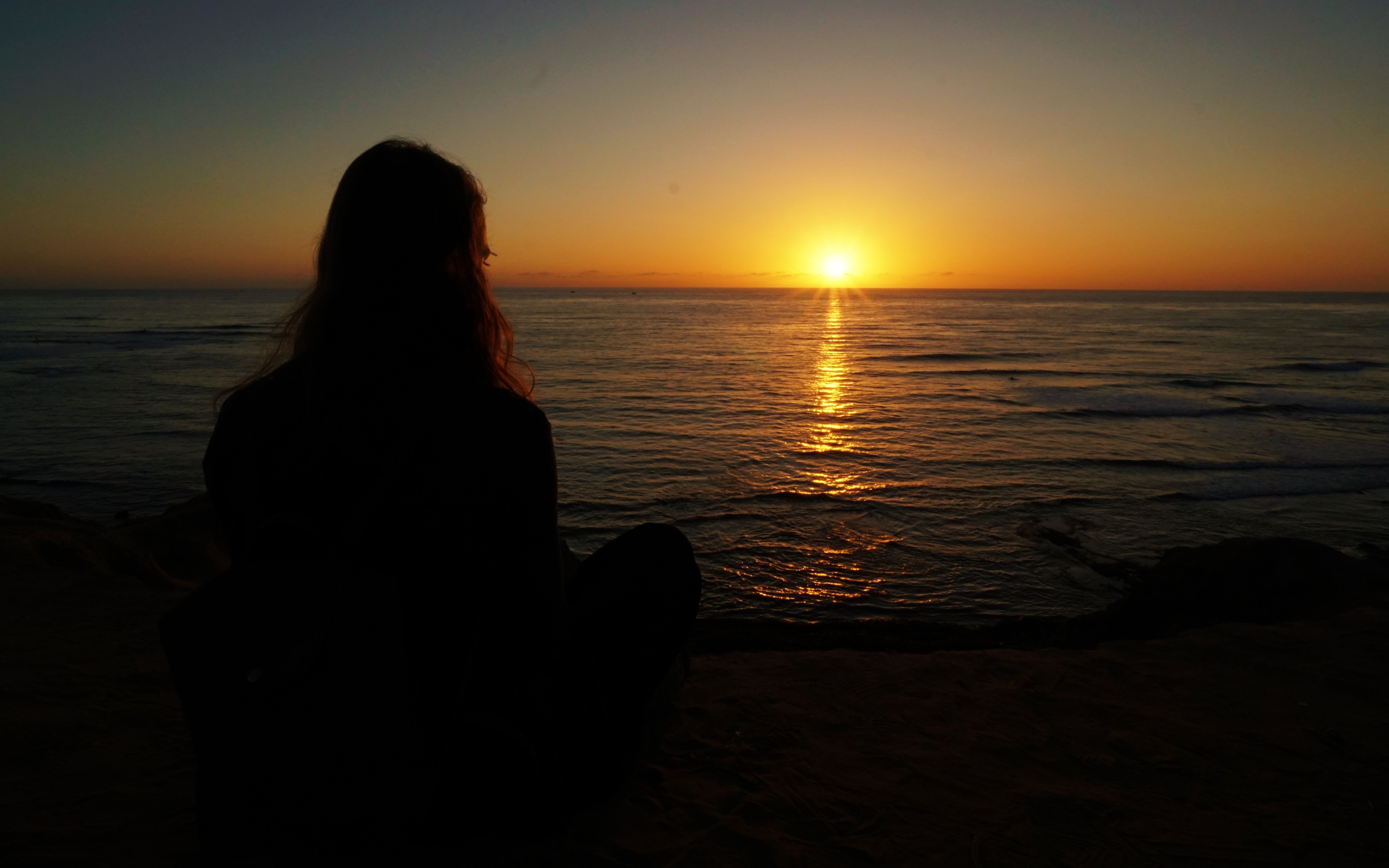 Girl watching sunset at Sunset Cliffs Natural Park, San Diego.