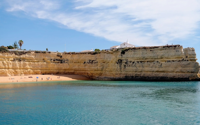 Benagil Caves coastline with sandy beach and cliffs in Algarve, Portugal.