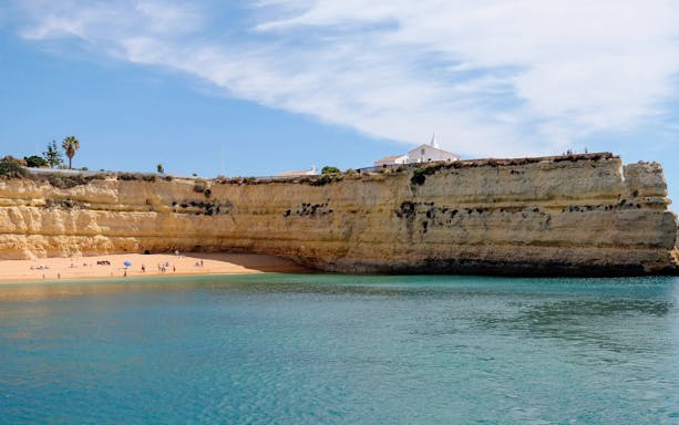 Benagil Caves coastline with sandy beach and cliffs in Algarve, Portugal.