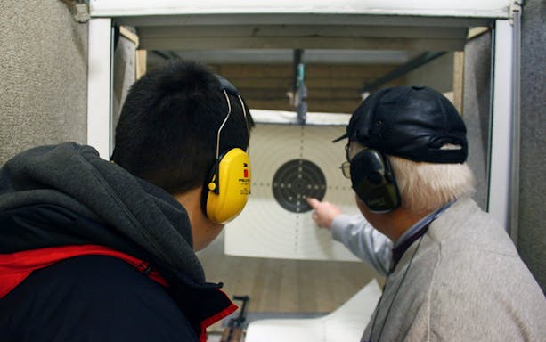 Two people at a shooting range in Gdansk, one pointing at a target.