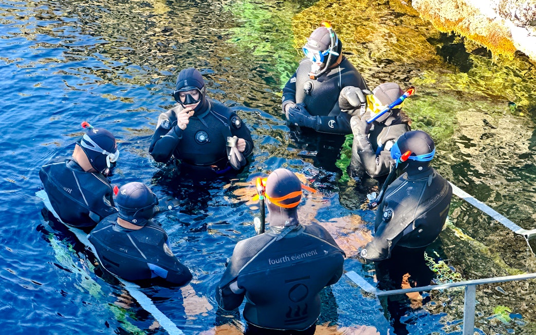 Guests preparing to snorkel in Silfra, Iceland, wearing wetsuits and snorkels.