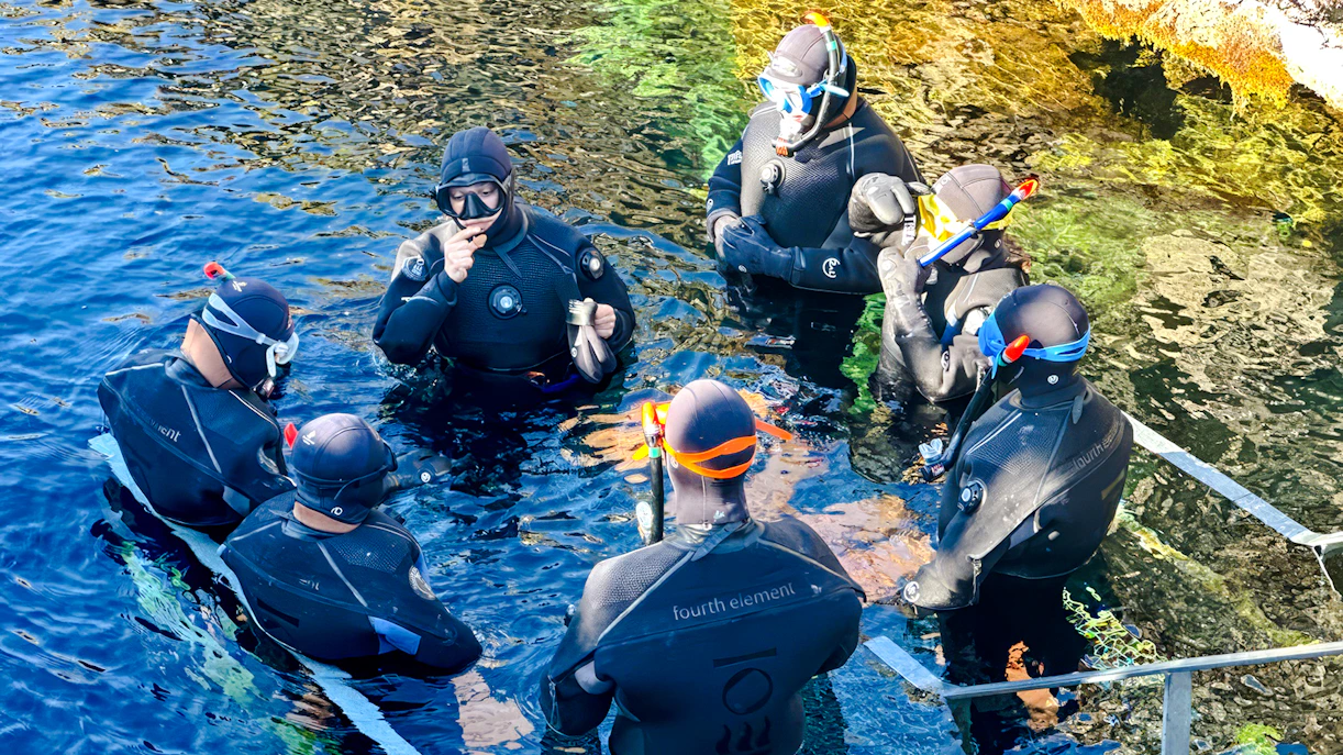 Guests preparing to snorkel in Silfra, Iceland, wearing wetsuits and snorkels.