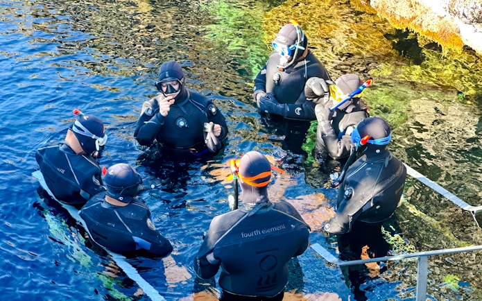 Guests preparing to snorkel in Silfra, Iceland, wearing wetsuits and snorkels.