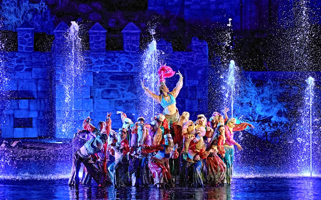 Performers in colorful costumes during The Dream of Toledo Night Show with fountains in the background.