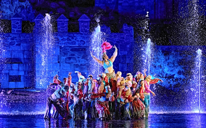 Performers in colorful costumes during The Dream of Toledo Night Show with fountains in the background.