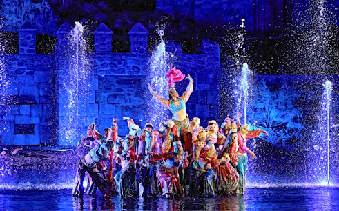 Performers in colorful costumes during The Dream of Toledo Night Show with fountains in the background.
