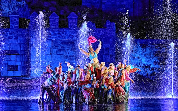 Performers in colorful costumes during The Dream of Toledo Night Show with fountains in the background.