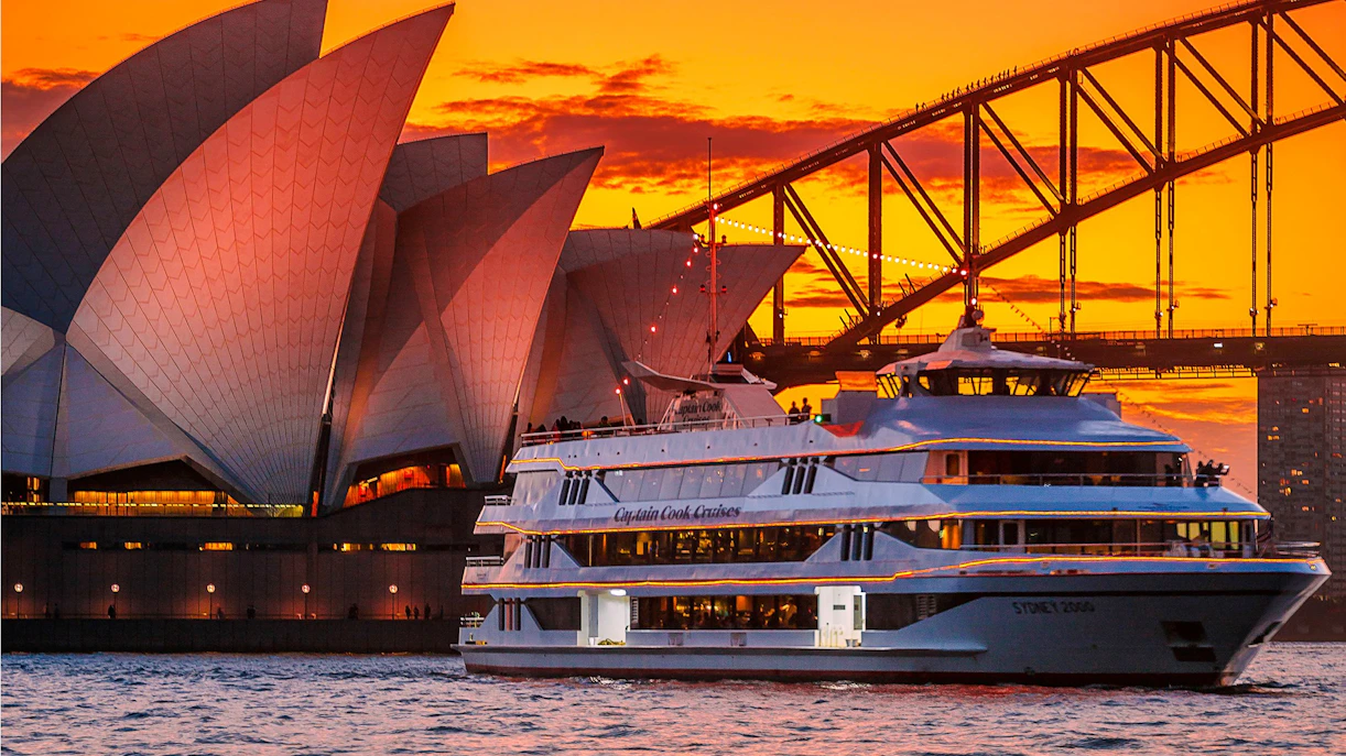Sydney Opera House and Harbour Bridge at sunset with cruise ship in foreground.