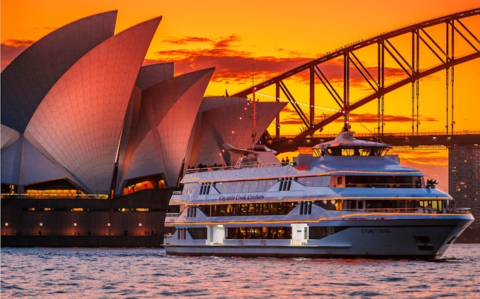 Sydney Opera House and Harbour Bridge at sunset with cruise ship in foreground.