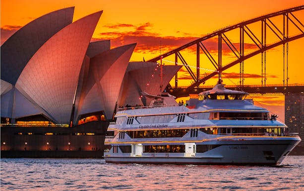 Sydney Opera House and Harbour Bridge at sunset with cruise ship in foreground.