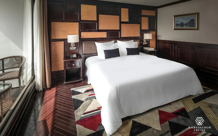 Luxurious bedroom on Ambassador Premium cruise with elegant decor and large window view.