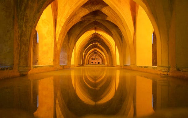 Alcazar Seville interior arches reflecting in water.