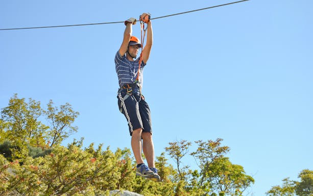 Person ziplining over trees in Split, Croatia.
