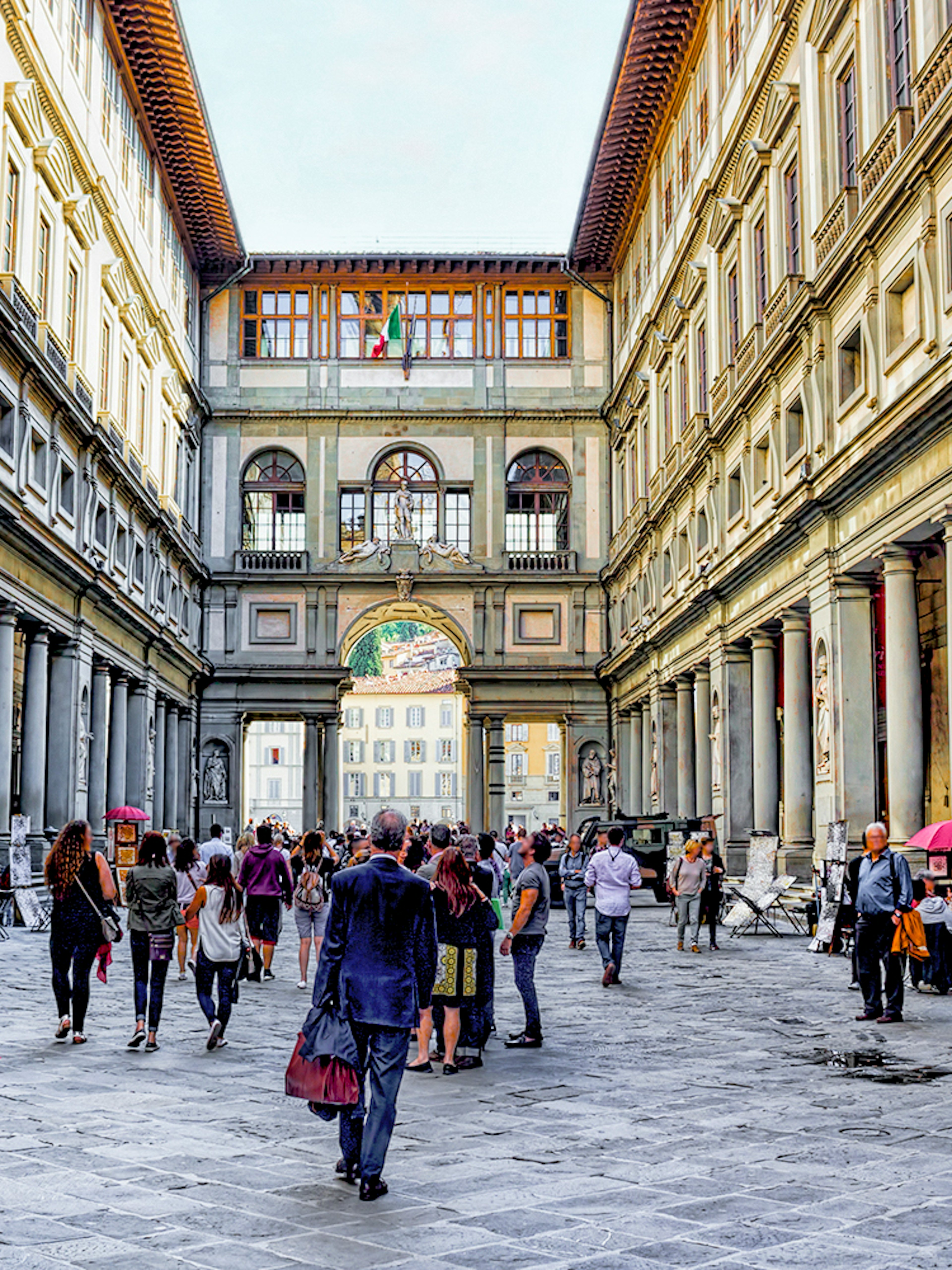 Visitors walking through the arcade of the Uffizi Gallery in Florence, Italy.