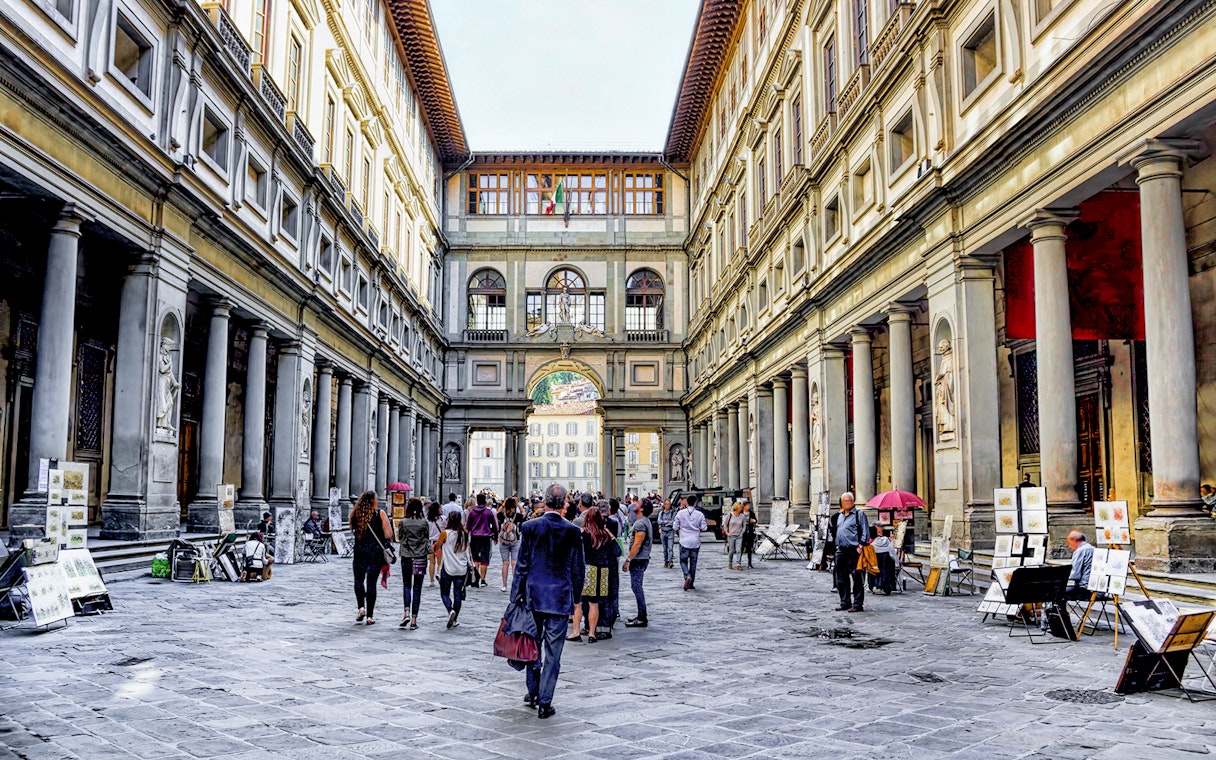 Visitors walking through the arcade of the Uffizi Gallery in Florence, Italy.