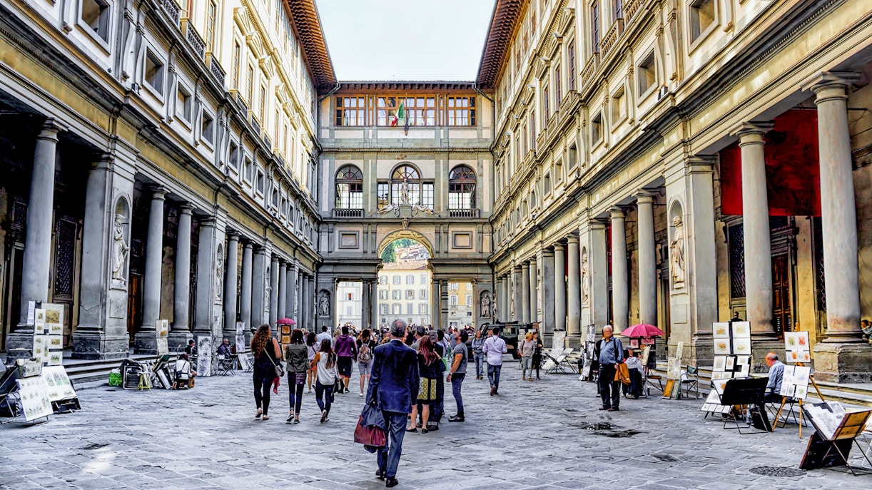 Visitors walking through the arcade of the Uffizi Gallery in Florence, Italy.