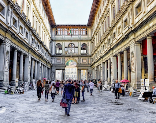 Visitors walking through the arcade of the Uffizi Gallery in Florence, Italy.