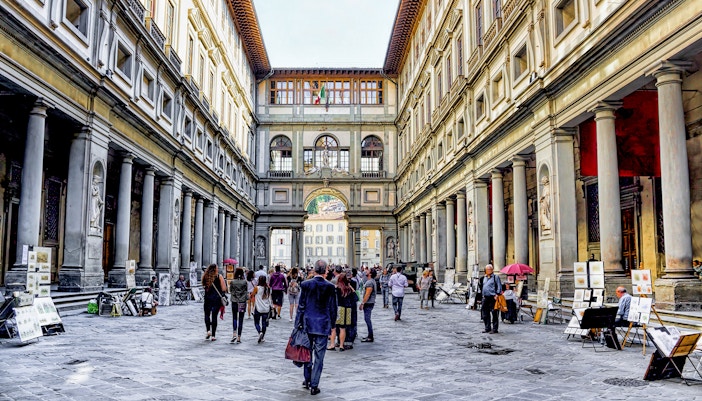 Visitors walking through the arcade of the Uffizi Gallery in Florence, Italy.