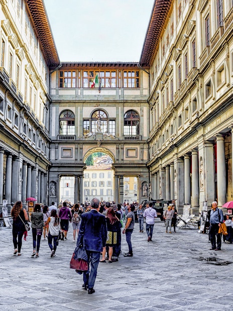 Visitors walking through the arcade of the Uffizi Gallery in Florence, Italy.