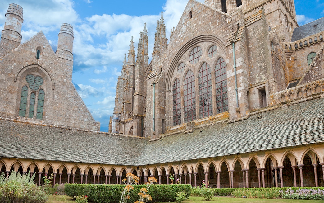 Mont-Saint-Michel Abbey cloister with stone arches and garden.