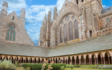 Mont-Saint-Michel Abbey cloister with stone arches and garden.
