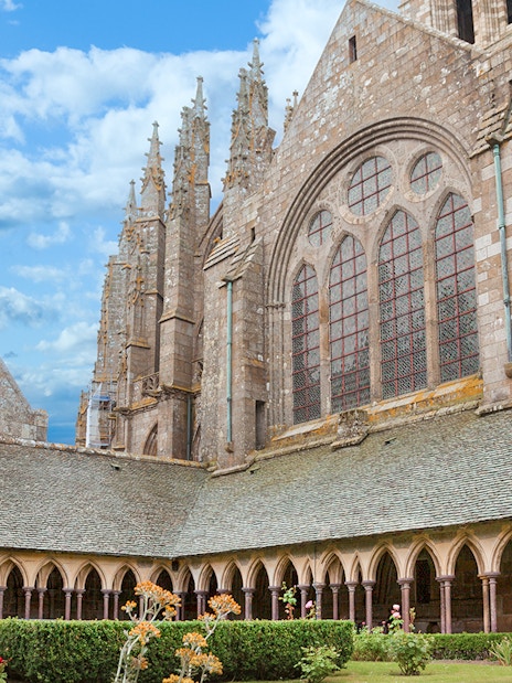 Mont-Saint-Michel Abbey cloister with stone arches and garden.