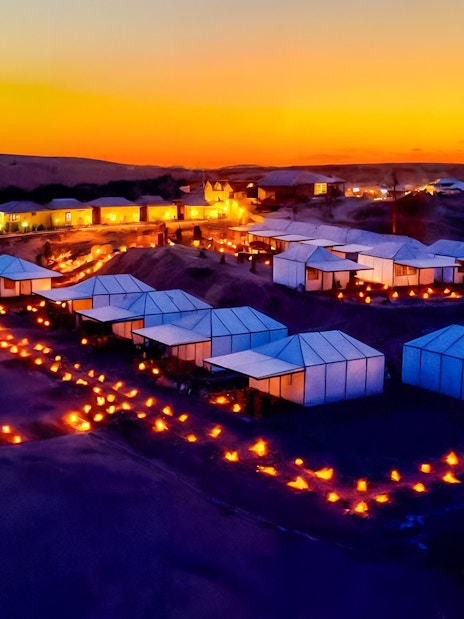 Marrakech Agafay desert camp illuminated at night with tents and lanterns.