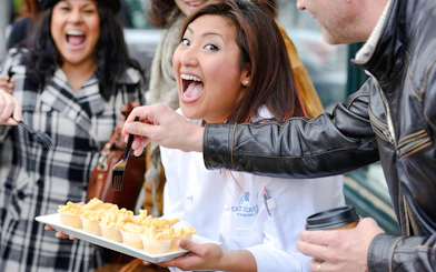 Chef leading a food tasting tour at Pike Place Market, Seattle, with participants sampling pasta.