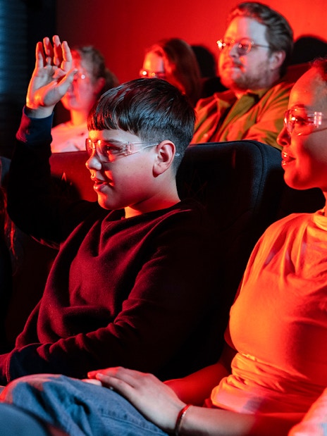 Guests watching the Lava show in Reykjavik theater, one raising hand.