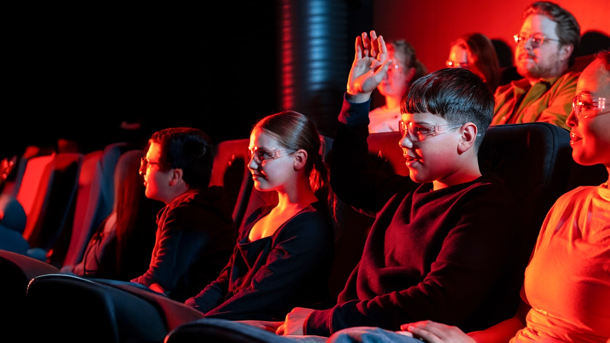 Guests watching the Lava show in Reykjavik theater, one raising hand.